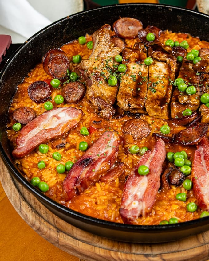 Paella suína servida na panela, com linguiça e ervilhas