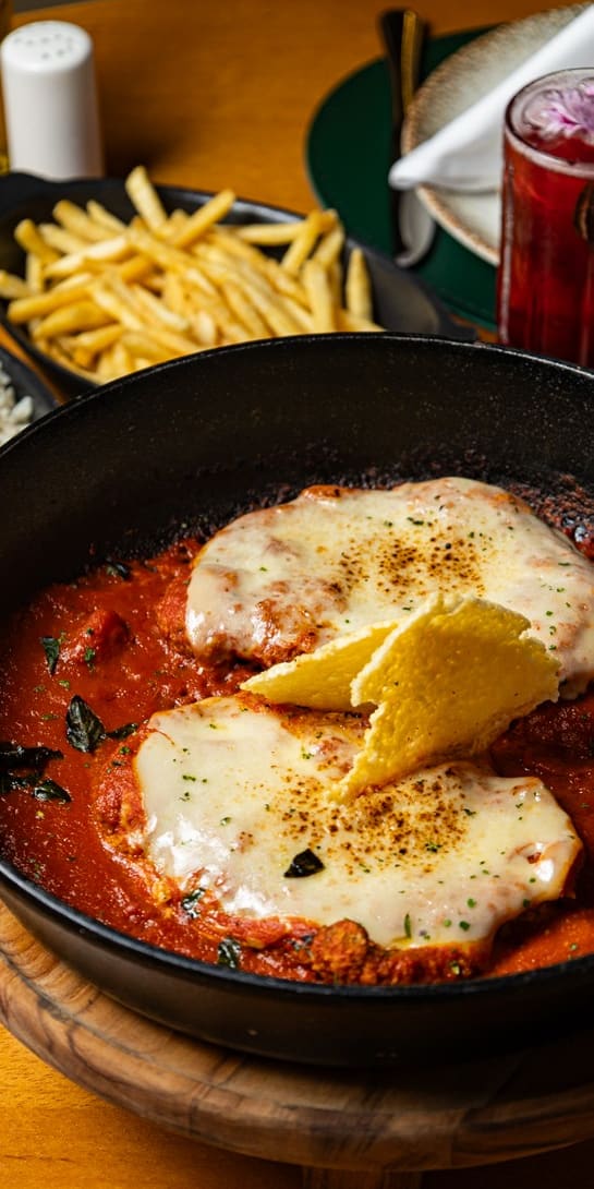 Bife à parmegiana do menu executivo, gratinado na frigideira